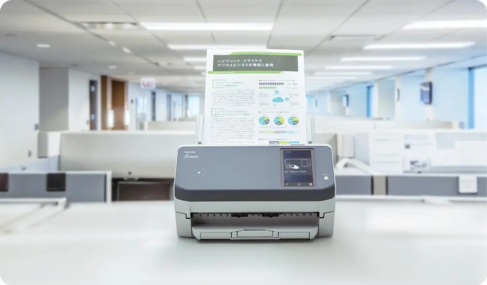 Office scanner on a desk in a modern, open workspace with cubicles and soft lighting, processing a document with graphs and text.