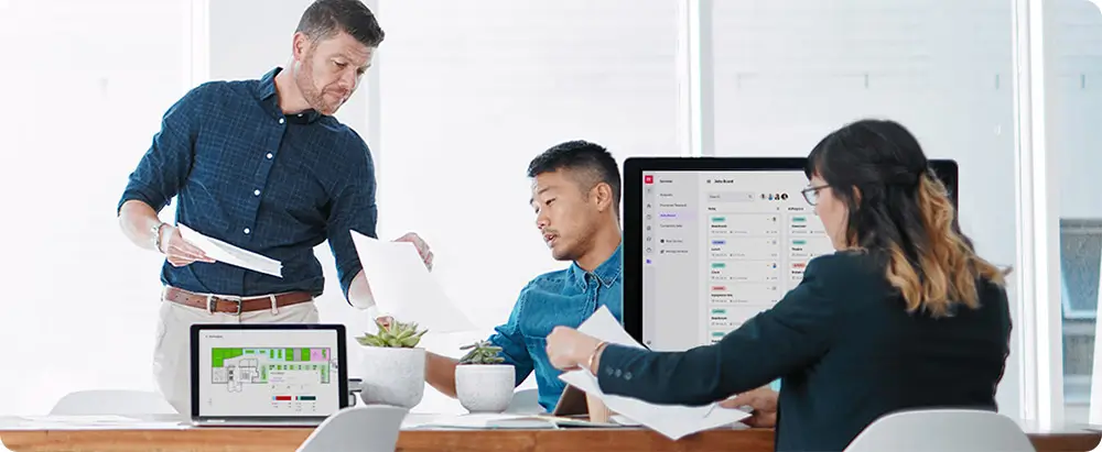 3 business people check work on paper and devices